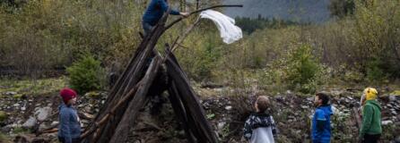 Ridgefield High School senior Tyson Ainsworth puts a rain poncho onto his group&#039;s shelter during a shelter-building exercise at the Cispus Learning Center. Ainsworth explained to the Sunset Ridge Intermediate School fifth graders that putting something noticeable like plastic or an item of clothing on top of your shelter can help draw attention to your location if a rescue helicopter is flying above you.