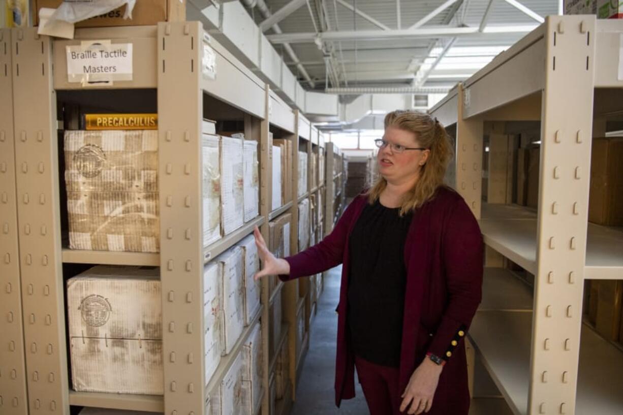 Braille program specialist and coordinator Kandi Lukowski describes the number of volumes it takes to make up one textbook at the Washington State School for the Blind&#039;s Ogden Resource Center. The precalculus book sitting on the top of the boxes is transcribed into six boxes of Braille volumes beneath it. Some textbooks can take more than a year to transcribe.