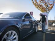 Pat David of Vancouver unplugs his Tesla at the Tesla Supercharger station in the Fred Meyer parking lot in Salmon Creek on Tuesday. David lives nearby and says he comes by this station often to get a faster charge and save on electricity costs.