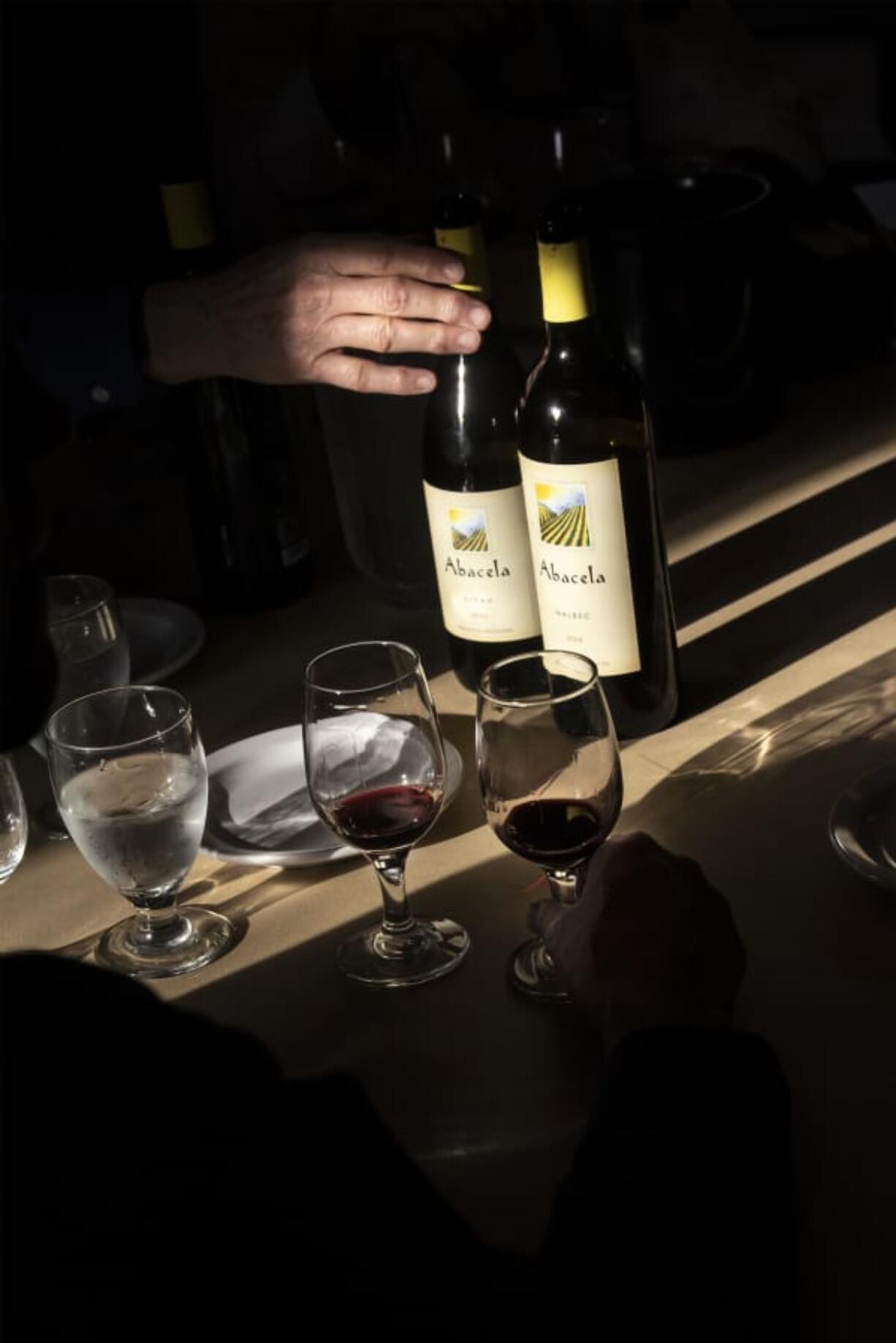 Ray Maddix, president of the Columbia Willamette Enological Society, reaches for a bottle of wine.