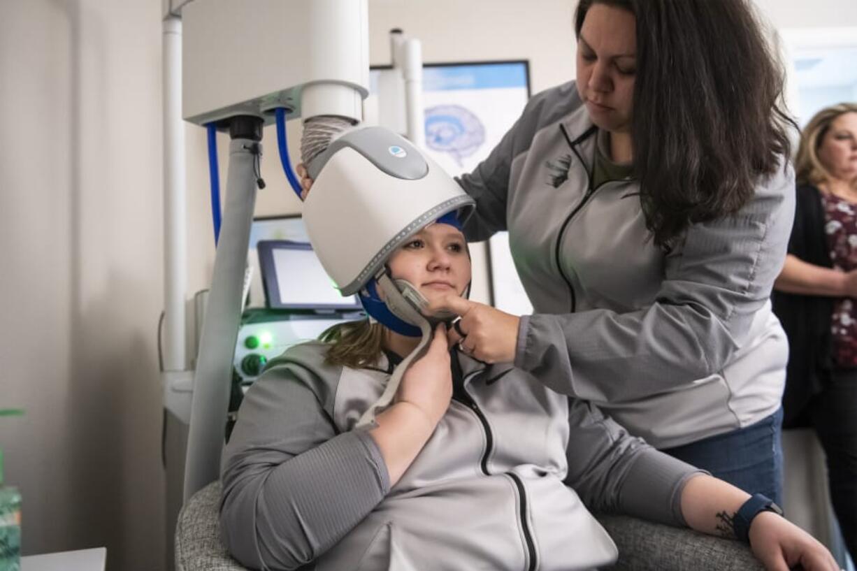 Tiffany Kraff, left, and Keri Rivera, technicians at TMS NW, demonstrate the deep transcranial magnetic stimulation machine at TMS NW in Vancouver. TMS spurs electronic activity that stimulates areas of the brain that are underactive in people with depression.