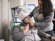 Tiffany Kraff, left, and Keri Rivera, technicians at TMS NW, demonstrate the deep transcranial magnetic stimulation machine at TMS NW in Vancouver. TMS spurs electronic activity that stimulates areas of the brain that are underactive in people with depression.