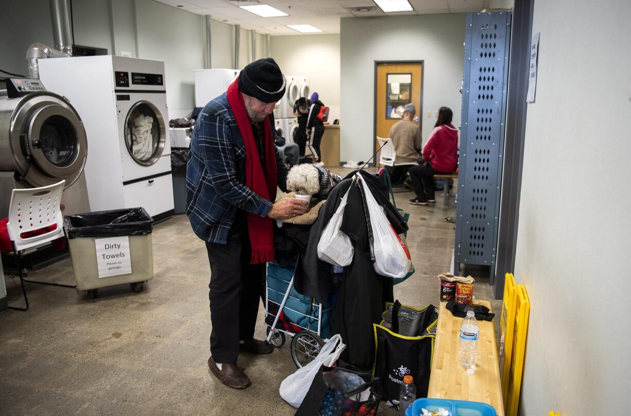 J.C. Ingram gives water to his dog Fritzy as he waits to use the showers at the Vancouver Navigation Center in Vancouver.