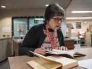 High school librarian Kate Burton flips through the 1943 Alki yearbook at Fort Vancouver High School, looking for a photo of Francis Elaine Bailey.