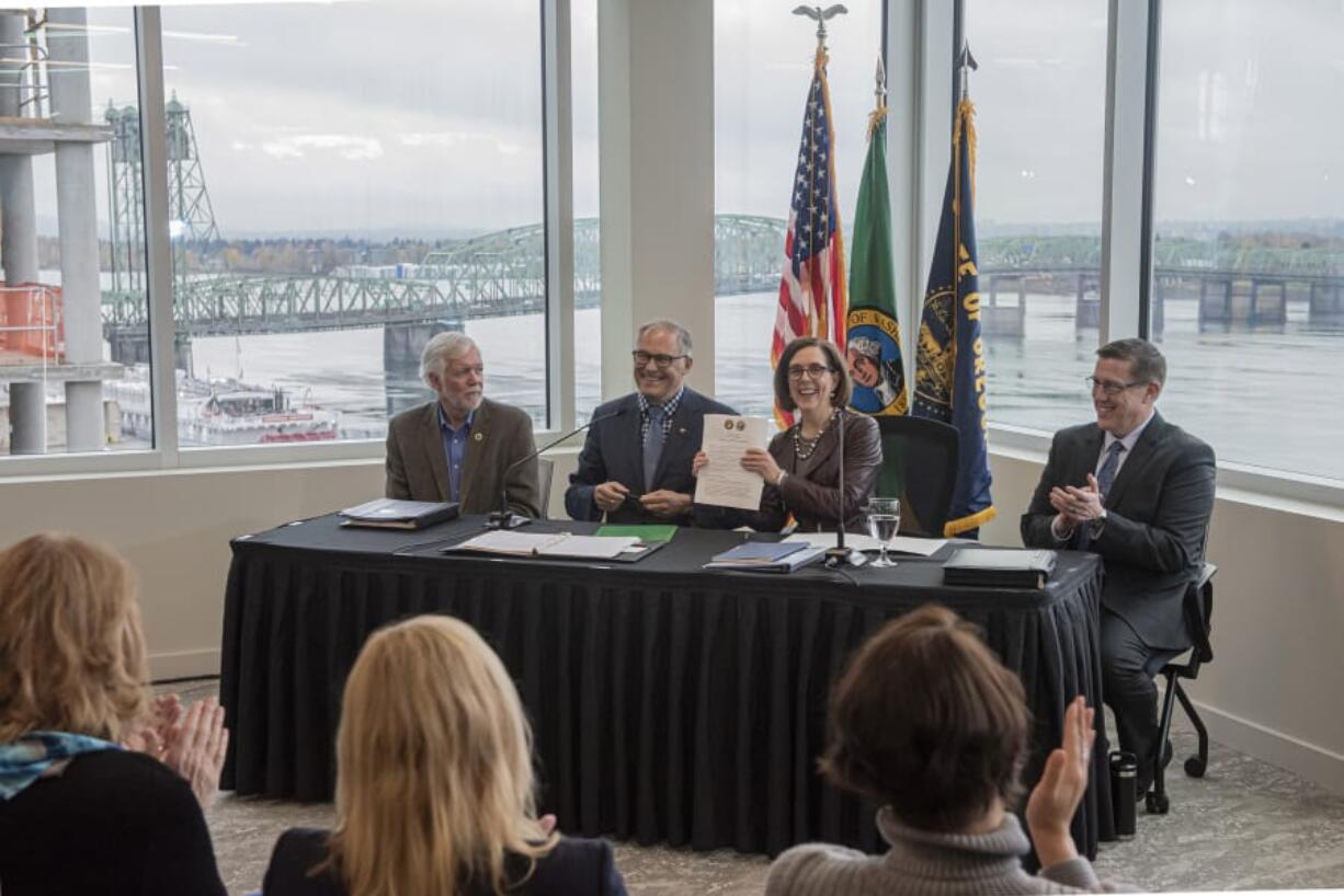 Roger Millar, Washington state secretary of transportation, from left, Washington Gov. Jay Inslee, Oregon Gov. Kate Brown and Kris Strickler, director of the Oregon Department of Transportation, applaud the signing of a memorandum of intent to replace the Interstate 5 bridge at the Murdock Charitable Trust on Monday morning, Nov. 18, 2019.