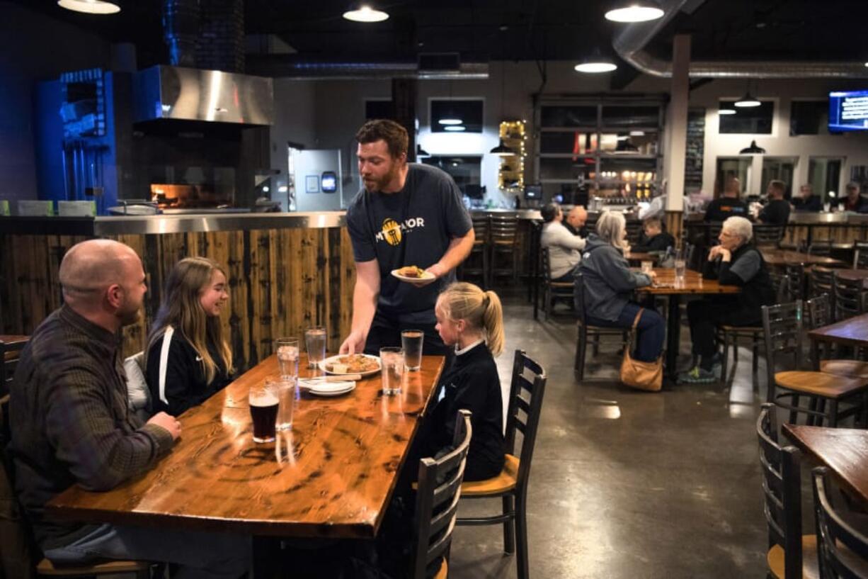 Bartender and server Garrett Lawler, center, serves customers at Mt. Tabor Brewing in Felida on Tuesday evening. Lawler said he&#039;s looking forward to the increase in minimum wage. &quot;It&#039;s absolutely fantastic,&quot; he said. Top: Lawler pours beer at Mt. Tabor Brewing.