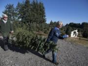 Loran, left, and Jane Larwick, both 65, haul what they say is an unsellable tree to be used instead for photo ops in Jane&#039;s shop. The two have run the 20-acre U-cut tree farm for 25 years, having lived at the property for just over 30 years.