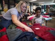 Vancouver Fire Department firefighter Kady Bieber, left, helps second-grader Erson Ermay pick out a new winter coat Thursday at Washington Elementary School in Vancouver. Firefighters with IAFF have partnered with Operation Warm to distribute more than 200,000 coats in more than 300 cities nationwide since 2012. Dutch Bros Coffee and Paul Davis Restoration partnered with Local 452 to help raise funds for this year's event.