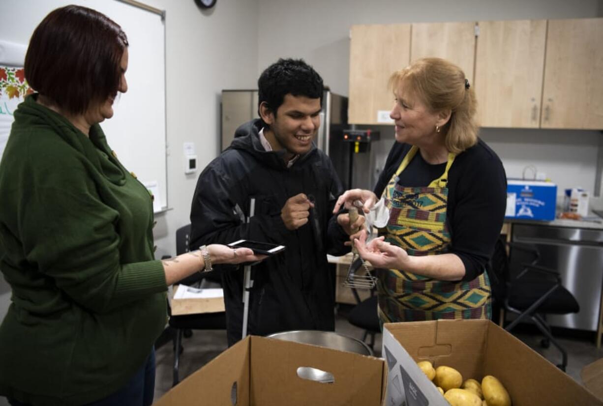 Vancouver Mayor Anne McEnerny-Ogle, right, orients Caples Terrace resident Miguel Viveros on the finer points of using a potato masher while case manager and self-sufficiency coordinator Jodi Freydenfeldt, left, records her instructions for later reference. Viveros has just moved into his first studio apartment at Caples Terrace, a new building at the Vancouver Housing Authority&#039;s Skyline Crest development, and he&#039;s eager to learn to cook. McEnerny-Ogle brought supplies and recipes so residents could cook and enjoy their own community Thanksgiving meal, later that day.