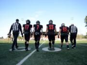 Camas football players Kolby Broadbent, left, Tyler Forner, Tristan Souza, and Tai Tumanuvao approach the coin toss before a game against Mount Si at McKenzie Stadium on Saturday afternoon, November 30, 2019. Camas beat Mount Si 35-14 to move on to the 4A state title game.