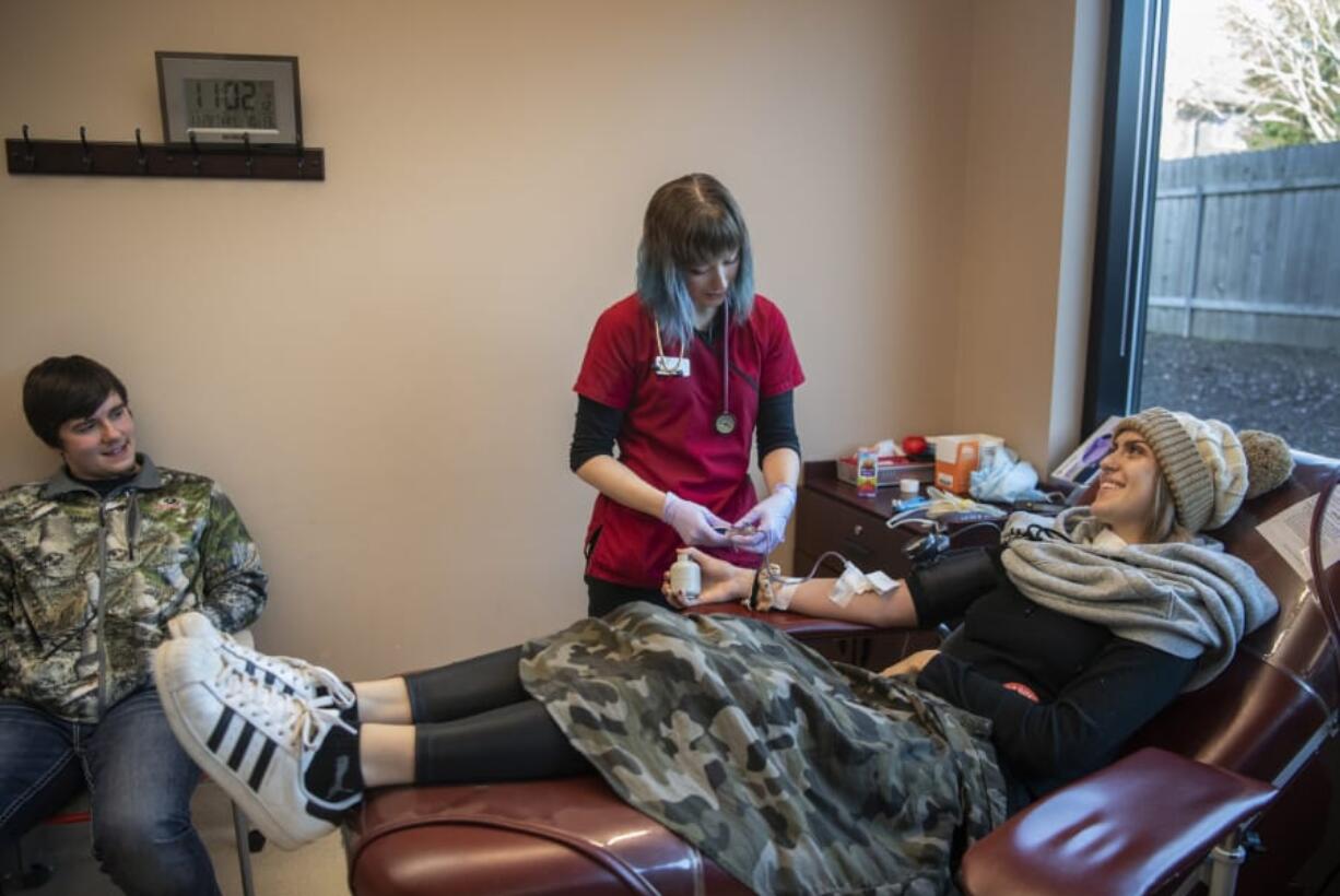 Dental hygiene student Brenna Weden, right, said an anatomy class has impressed her with how important it is to give blood. So she drove down from Kalama with boyfriend Joshua St. Peter, left, to give blood on Thanksgiving morning at the American Red Cross Blood Donation Center near the Vancouver Mall. Phlebotomist Reese Miller, center, said more than 50 people were expected to donate blood before the event was over.