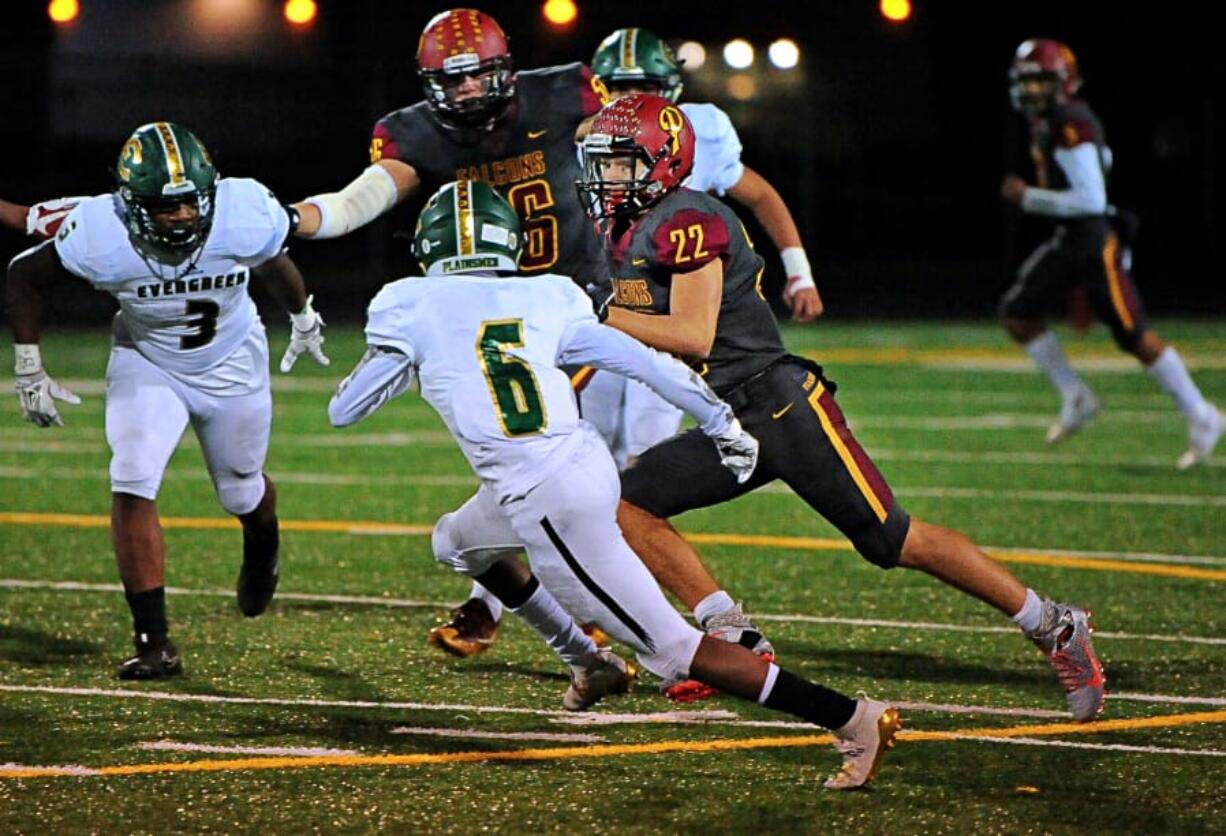 Prairie running back Dustin Shelby ran for 141 yards on 17 carries, including this run past Evergreen&#039;s Jonathan Simon (6) and Derrick Webb (3) in the Falcons&#039; 42-14 win over Evergreen on Friday at District Stadium in Battle Ground. The win secures Prairie&#039;s first league title since 1992.