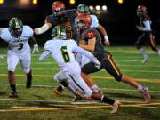 Prairie running back Dustin Shelby ran for 141 yards on 17 carries, including this run past Evergreen&#039;s Jonathan Simon (6) and Derrick Webb (3) in the Falcons&#039; 42-14 win over Evergreen on Friday at District Stadium in Battle Ground. The win secures Prairie&#039;s first league title since 1992.