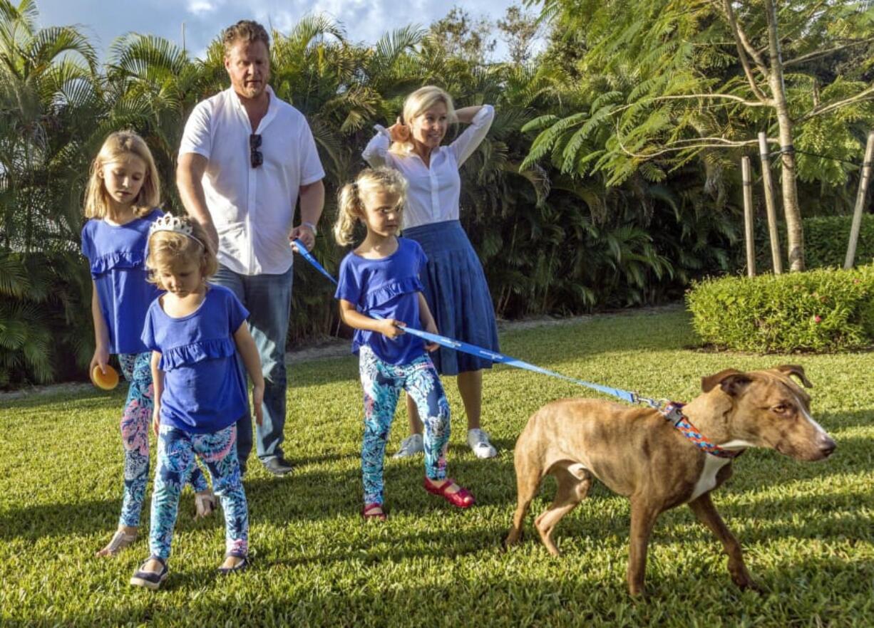 Miracle, the dog pulled from the rubble in Marsh Harbor after Hurricane Dorian, and his new family head outside after a ceremony Tuesday at Big Dog Ranch Rescue in Loxahatchee, Fla.