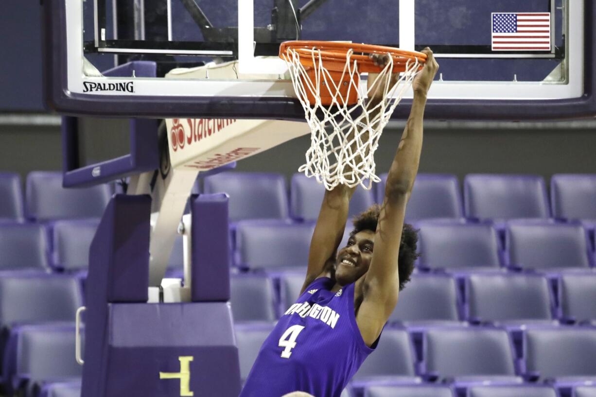 In this photo taken Tuesday, Oct. 22, 2019, Washington forward Jaden McDaniels playfully hangs from a basket before a team photo during the basketball team's media day in Seattle.