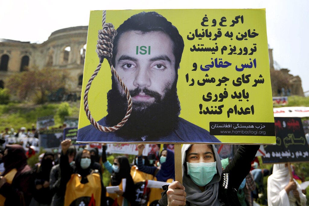 File- in this Tuesday, April 26, 2016. photo, a protester holds a poster with Persian that reads,"If Ghani and Abdullah do not betray the terrorist attacks' victims, they should execute Anas Haqqani and the other terrorist leaders who have been arrested" during a demonstration in Kabul, Afghanistan. Afghan President Ghani said Tuesday, Nov. 12, 2019, that his government has released three Taliban figures in effort to have the insurgents free an American and an Australian professor they abducted in 2017.