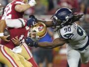 San Francisco 49ers quarterback Jimmy Garoppolo, left, avoids being sacked by Seattle Seahawks defensive end Jadeveon Clowney (90) during the second half of an NFL football game in Santa Clara, Calif., Monday, Nov. 11, 2019.