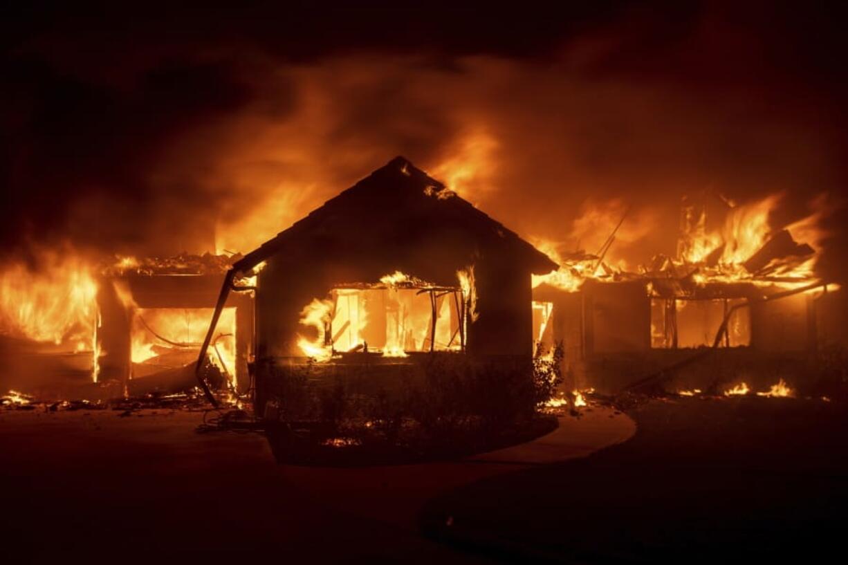 FILE - In this Oct. 31, 2019 file photo flames from the Hillside Fire consume a home in San Bernardino, Calif. President Donald Trump on Sunday, Nov. 3 threatened to cut U.S. funding to California for aid during wildfires that have burned across the state during dry winds this fall.