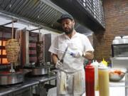 In this Wednesday, Oct. 9, 2019, photo, chef Diaa Alhanoun sharpens his knives between serving customers, while skewered pieces of cooked chicken and beef known, or &quot;shawarma,&quot; are kept warm at his restaurant Sakib, in New York. A Syrian refugee fleeing civil war at home, Alhanoun, his wife and four children arrived in the U.S. from Jordan in 2016. Less than three years later Alhanoun and a partner opened a small restaurant in Brooklyn&#039;s trendy Williamsburg neighborhood.