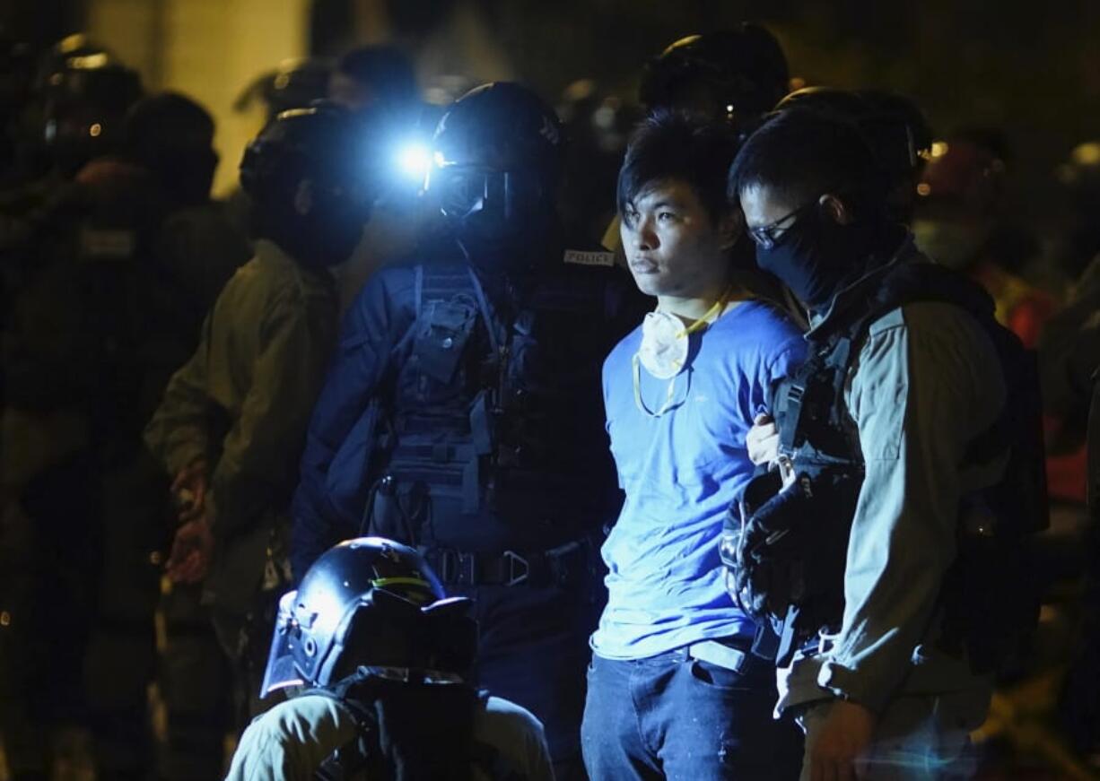 Riot police detain a protestor after he tried to escape from Hong Kong Polytechnic University in Hong Kong, Tuesday, Nov. 19, 2019. About 100 anti-government protesters remained holed up at a Hong Kong university Tuesday, their choices dwindling along with their food supplies as they braced for the endgame in a police siege of the campus that entered its third day.