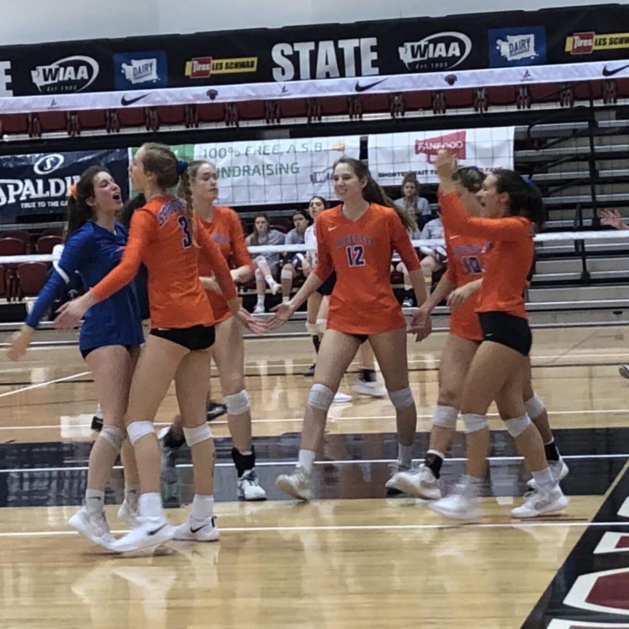 The Ridgefield volleyball team, including Emily Vossenkuhl (12) celebrate a point during a first-round victory over River Ridge at the 2A state tournament on Friday in Ellensburg.