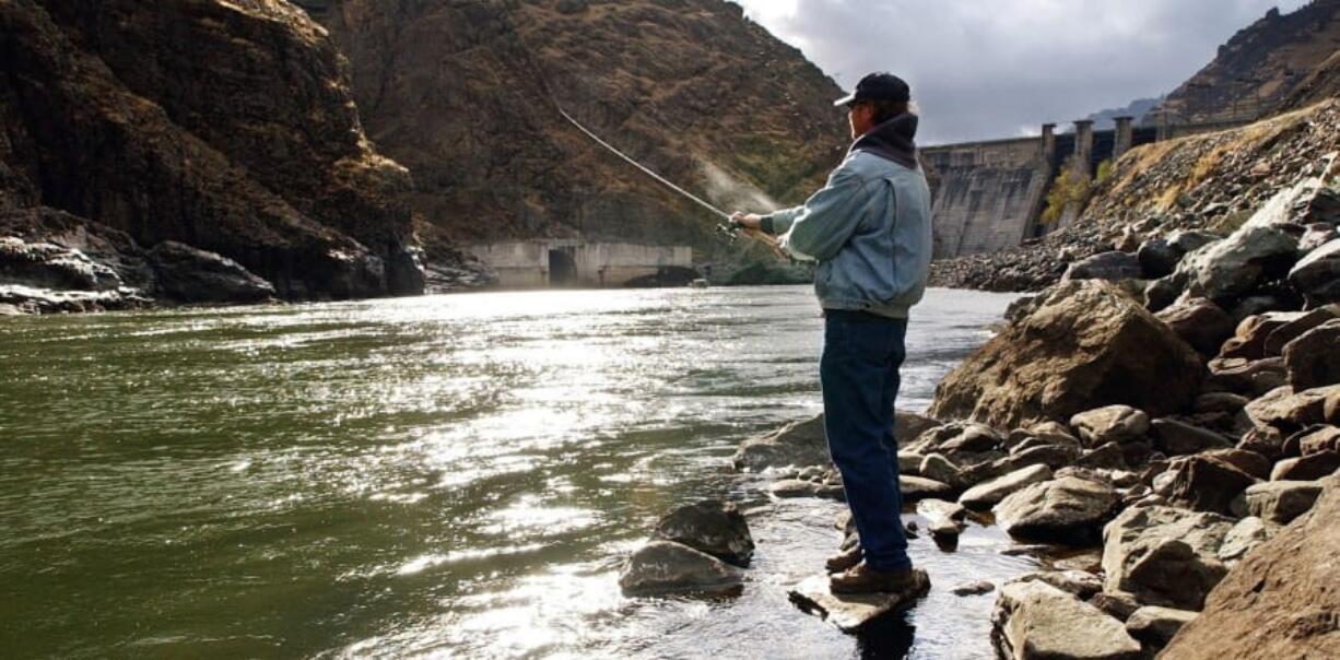 FILE - In this Nov. 16, 2003, file photo, fisherman Larry McBrom works along the Snake River shoreline below Hells Canyon Dam in southwestern Idaho. An Idaho utility will voluntarily dismiss its lawsuit against the U.S. Environmental Protection Agency involving relicensing of the company&#039;s hydroelectric project where federally protected fall chinook salmon reproduce. Idaho Power in documents filed recently in U.S. District Court says the EPA in response to the lawsuit has approved allowing warmer water temperatures in the Snake River below the Hells Canyon Complex on the Idaho-Oregon border.