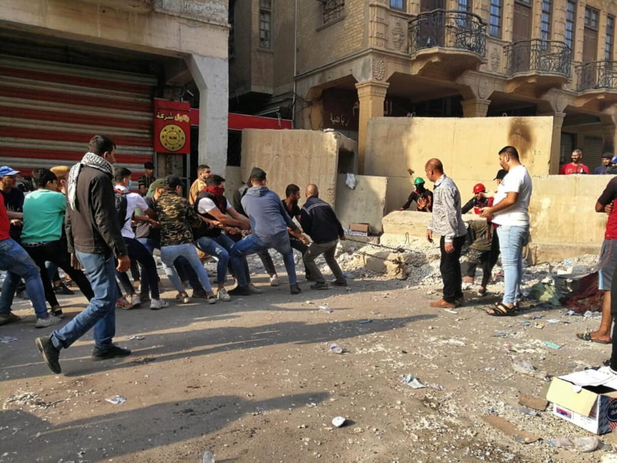 Anti-government protesters pull down concrete walls in downtown Baghdad, Iraq, Monday, Nov. 18, 2019.