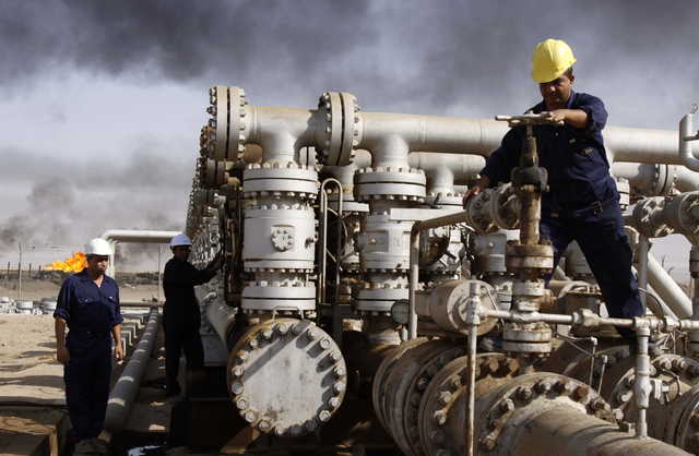 In this Dec. 13, 2009 file photo, men work at the Rumaila oil refinery, near the Iraqi city of Basra. Iraq is rich in oil, but protesters say they don’t see the fruits of this wealth. Fueling the unrest is anger over an economy flush with oil money that has failed to bring jobs or improvements to the lives of young people, who are the majority of those taking to the streets.