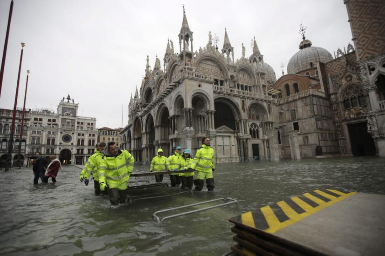 Municipality workers carry wooden boards to create a trestle bridge in a flooded St. Mark&#039;s Square at Venice, Friday, Nov. 15, 2019. The high-water mark hit 187 centimeters (74 inches) late Tuesday, Nov. 12, 2019, meaning more than 85% of the city was flooded. The highest level ever recorded was 194 centimeters (76 inches) during infamous flooding in 1966.