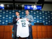 Seattle Mariners general manager Jerry Dipoto, left, and new first baseman Evan White pose for photographs with White's new jersey after a news conference at T-Mobile Park Monday, Nov. 25, 2019 in Seattle.