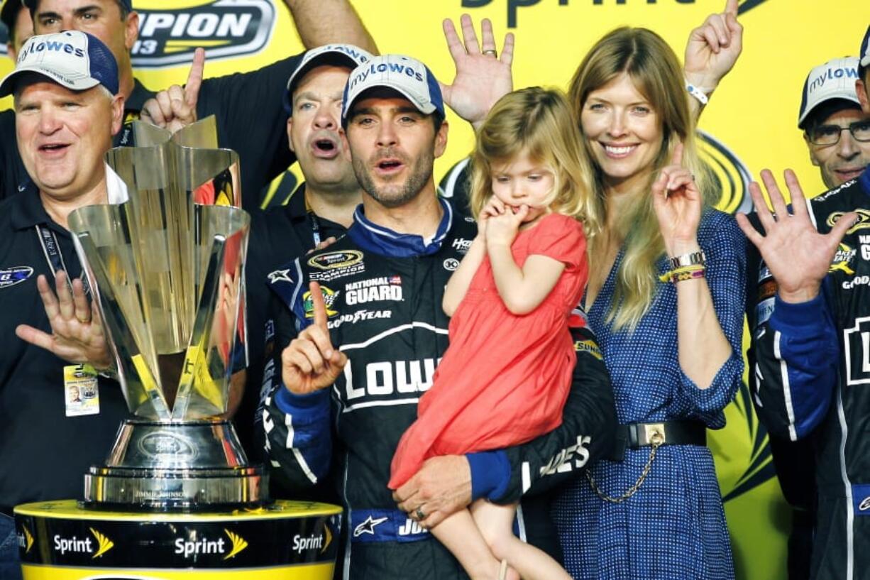 FILE - In this Nov. 17, 2013, file photo, Jimmie Johnson, center, his wife, Chandra, and his daughter, Genevieve, celebrate after he won his sixth NASCAR Sprint Cup Series championship, in Homestead, Fla. Jimmie Johnson is the latest NASCAR superstar to climb out of his car, with the seven-time champion announcing Wednesday, Nov. 20, 2019, that 2020 will be his final season of full-time racing.