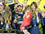 FILE - In this Nov. 17, 2013, file photo, Jimmie Johnson, center, his wife, Chandra, and his daughter, Genevieve, celebrate after he won his sixth NASCAR Sprint Cup Series championship, in Homestead, Fla. Jimmie Johnson is the latest NASCAR superstar to climb out of his car, with the seven-time champion announcing Wednesday, Nov. 20, 2019, that 2020 will be his final season of full-time racing.