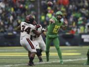 Oregon quarterback Justin Herbert (10) throws a pass away from Oregon State inside linebacker Avery Roberts (34) and defensive lineman Simon Sandberg (45) during the second half of an NCAA college football game in Eugene, Ore., Saturday, Nov. 30, 2019.