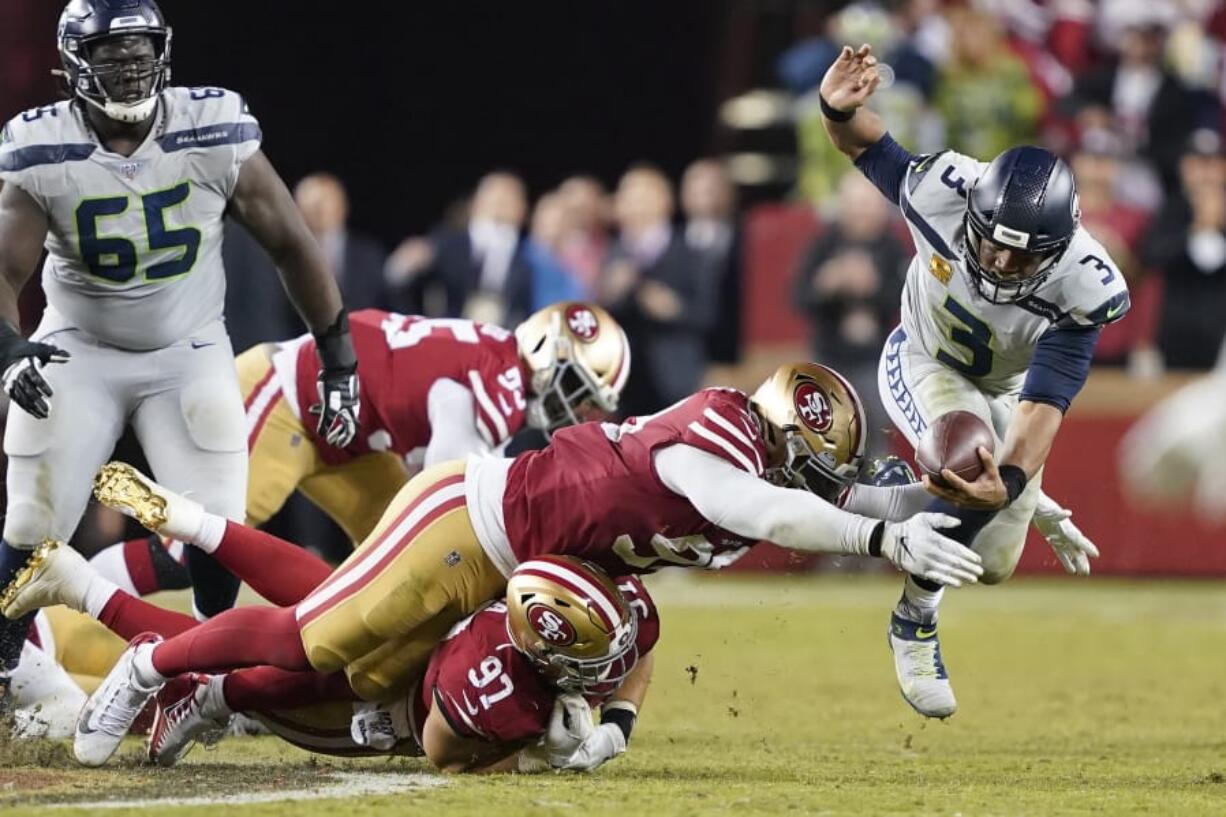 Seattle Seahawks quarterback Russell Wilson (3) scrambles away from San Francisco 49ers defenders during overtime of an NFL football game in Santa Clara, Calif., Monday, Nov. 11, 2019. Wilson was ruled sacked on the play.