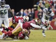 Seattle Seahawks quarterback Russell Wilson (3) scrambles away from San Francisco 49ers defenders during overtime of an NFL football game in Santa Clara, Calif., Monday, Nov. 11, 2019. Wilson was ruled sacked on the play.