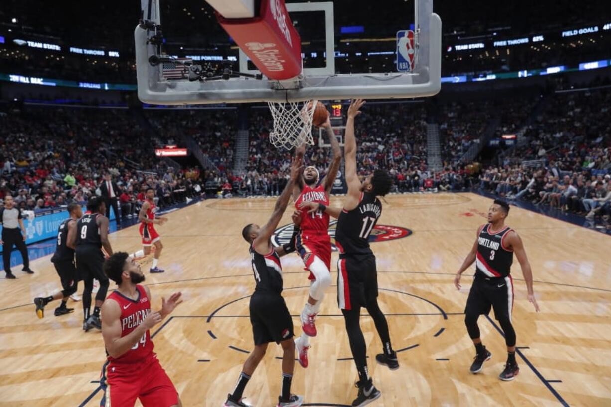 New Orleans Pelicans forward Brandon Ingram (14) goes to the basket between Portland Trail Blazers forward Skal Labissiere (17) and guard Kent Bazemore in the second half of an NBA basketball game in New Orleans, Tuesday, Nov. 19, 2019. The Pelicans won 115-104.