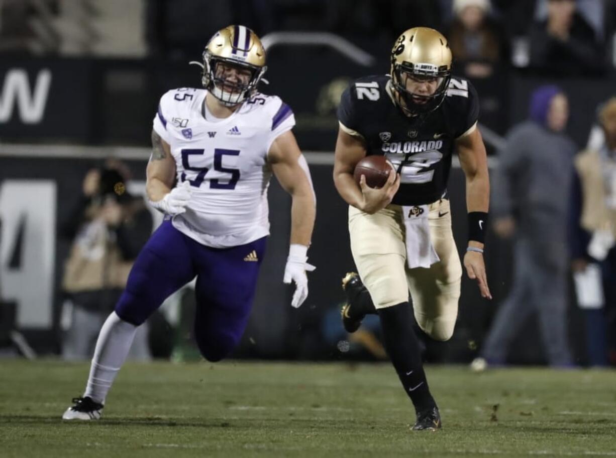 Colorado quarterback Steven Montez runs for a short gain as Washington linebacker Ryan Bowman pursues during the first half of an NCAA college football game Saturday, Nov. 23, 2019, in Boulder, Colo.