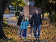 Sarah, from left, Vivian, Lucy and Chris Collmer walk their dog, Teddy, in the Hough neighborhood of Vancouver. The Collmer family tries to walk for excursions downtown to reduce carbon emissions. Sarah Collmer said they have come to really enjoy this time together. &quot;You notice more things and connect with the community more,&quot; she said.