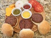 Beyond Beef, from left, Impossible Burger and regular beef burger cooked and presented with condiments.