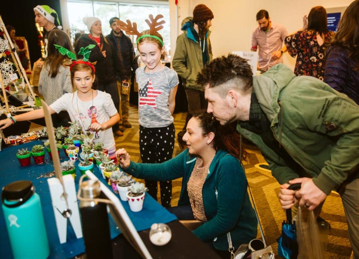 Sophia Campbell, 7, of Portland, and Emily Corsen, 9, of Vancouver, talk to Samantha Duenas, of Los Angeles, and Aaron Ferrara, of Vancouver, about the succulents and hand-painted pots they have for sale on Sunday during the Vancouver Farmers Market Holiday Market at the Hilton Vancouver Washington.