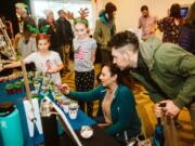 Sophia Campbell, 7, of Portland, and Emily Corsen, 9, of Vancouver, talk to Samantha Duenas, of Los Angeles, and Aaron Ferrara, of Vancouver, about the succulents and hand-painted pots they have for sale on Sunday during the Vancouver Farmers Market Holiday Market at the Hilton Vancouver Washington.