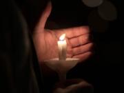 A vigil participant blocks the breeze to keep his candle lit in honor of Tiffany Hill on Sunday night at Esther Short Park in Vancouver.