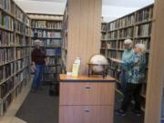 Marcia Grubb, from left, education director for the Clark County Genealogical Society, looks through books in the library of the organization&#039;s new facility with volunteers Sharon Cleveland and Barbara Schrag on Thursday.