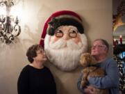 Janis and Marty Bell pose for a photo with their Havanese, Molly, in front of a Katherine&#039;s Collection wooden Santa at their home in Yacolt on Monday. Every room in the house is filled with a variety of Christmas decorations that Janis Bell has collected over the past 50 years.