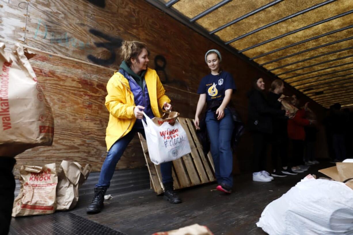 Roxie Olsen, left, passes donated food to Ali Parmenter during the Walk &amp; Knock food drive on Saturday at Chuck&#039;s Produce. Olsen previously served as a Walk &amp; Knock board member for 15 years. Now, she continues to volunteer.