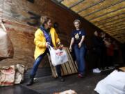 Roxie Olsen, left, passes donated food to Ali Parmenter during the Walk &amp; Knock food drive on Saturday at Chuck&#039;s Produce. Olsen previously served as a Walk &amp; Knock board member for 15 years. Now, she continues to volunteer.