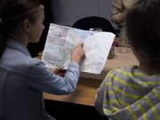 Anna Demchukov, 13, traces the outline of a building on a hand-drawn city plan while working on a future city at River HomeLink on Friday afternoon.