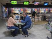 Rachael and Don Allen, owners of Allen's Crosley Lanes, chat inside their bowling alley as customers test their skill nearby Wednesday. A yearlong moratorium on new development along Evergreen and Grand boulevards has taken property owners by surprise, including the Allens, who had a buyer on the property fall through as a result. The family has owned and operated the bowling alley since 1987.