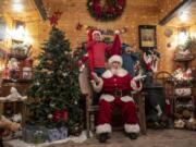 Connar Williams, 11, from left, Santa Claus, played by Brian Trembley, and Gage Williams 6, pose for a photo in Trembley&#039;s Santa Chalet in Woodland.