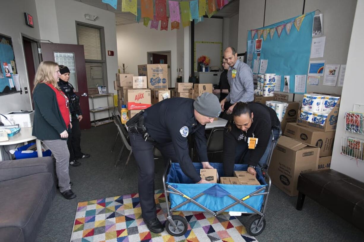 Jenny Thompson, executive director of the Police Activities League of Southwest Washington, from left, helps organize donations for families at Discovery Middle School with Officer Danielle Wass, Lt. Doug Luse and Walmart Neighborhood Market Assistant Manager Leanne Younger before Christmas. Drew Schoening, in black shirt, and David Mack of Walmart Neighborhood Market also helped. The &quot;essentials drive&quot; is one of several holiday events Thompson organizes.